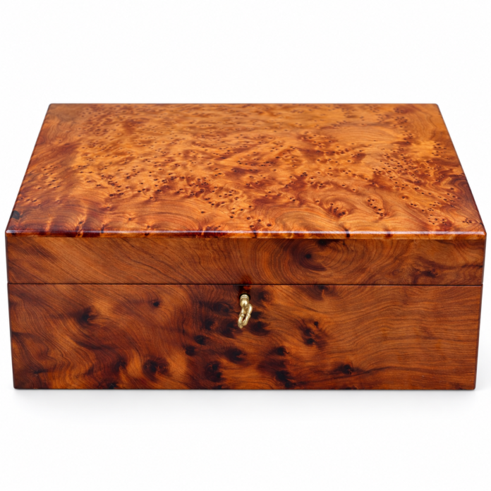 Closed thuya wood jewellery box with swirling burl grain and a small key in the front lock.